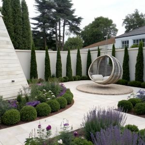 A large urban garden with white stone paths, rows of topiaried box and yew, lavender, a pyramid shed, and a rattan swing chair.